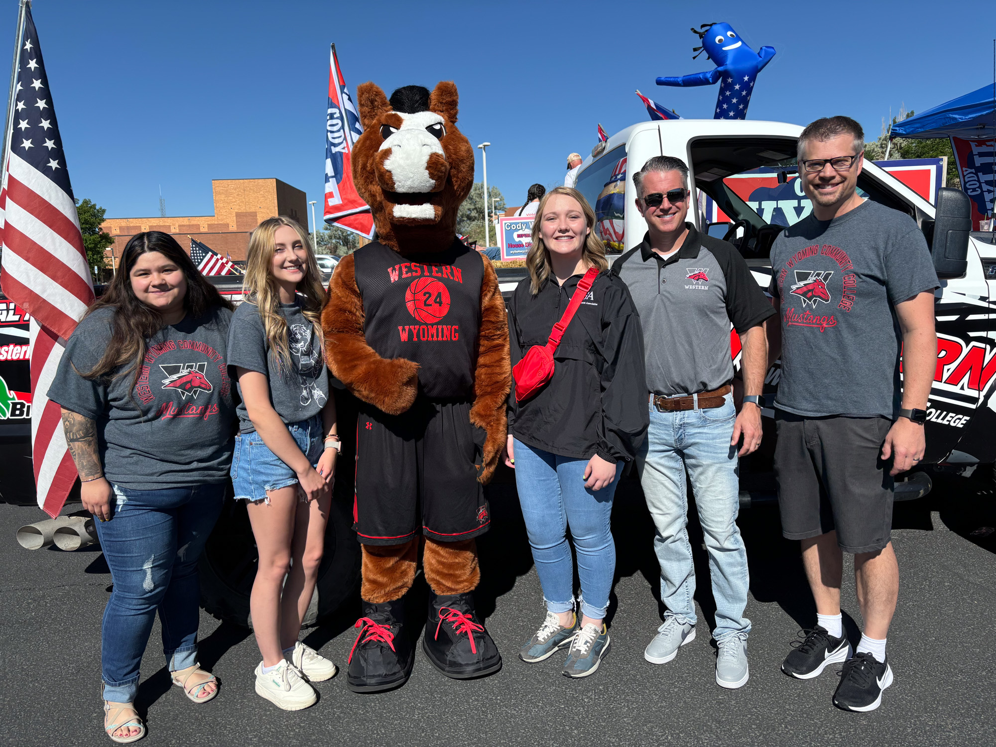 Group photo of Dr. Kirk Young with Maverick the Mascot, Dr. Dustin Conover, Xitlaly Chavarria and two students during the 4th of July Parade