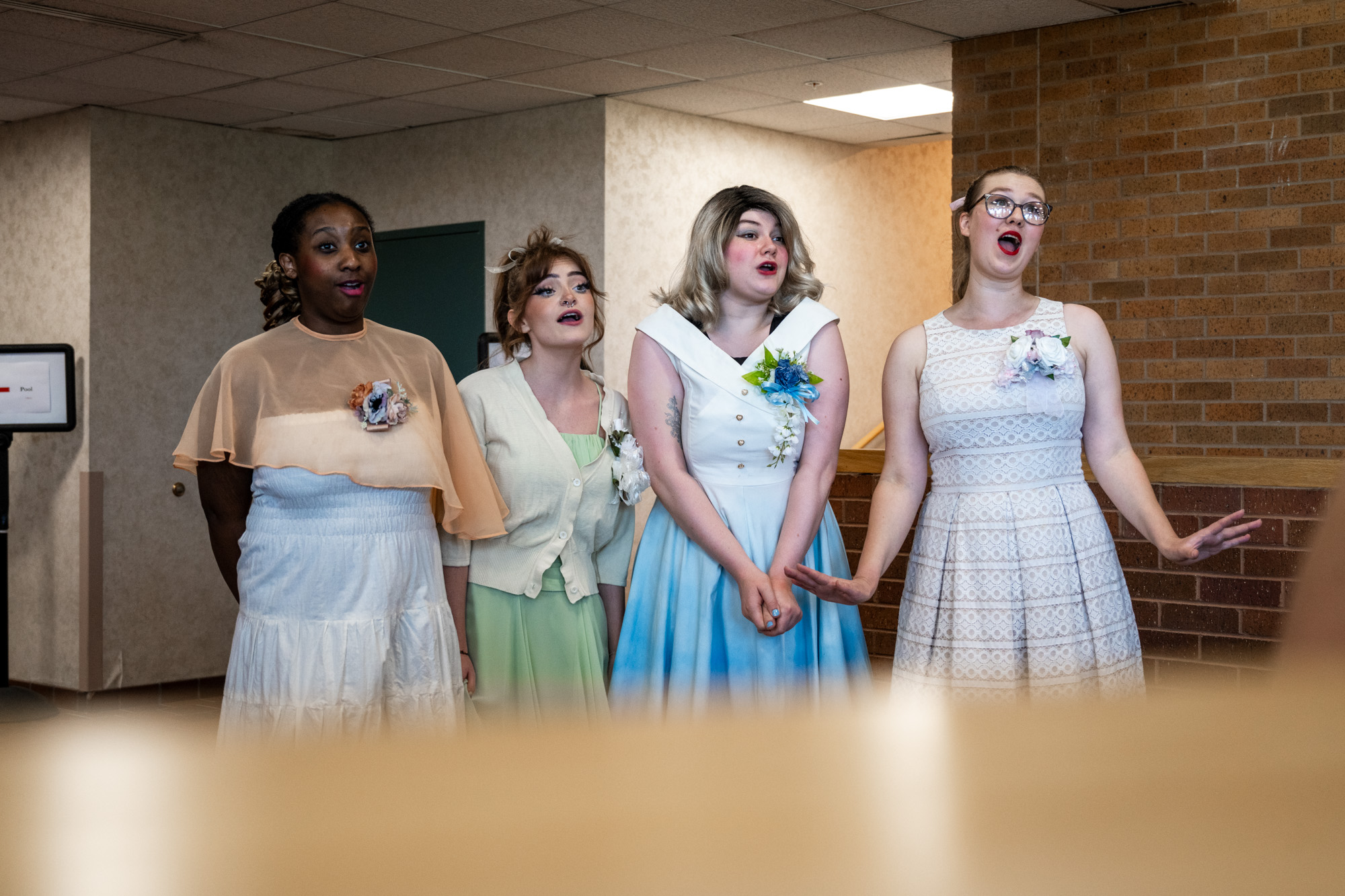 Four theatre performers singing in a line