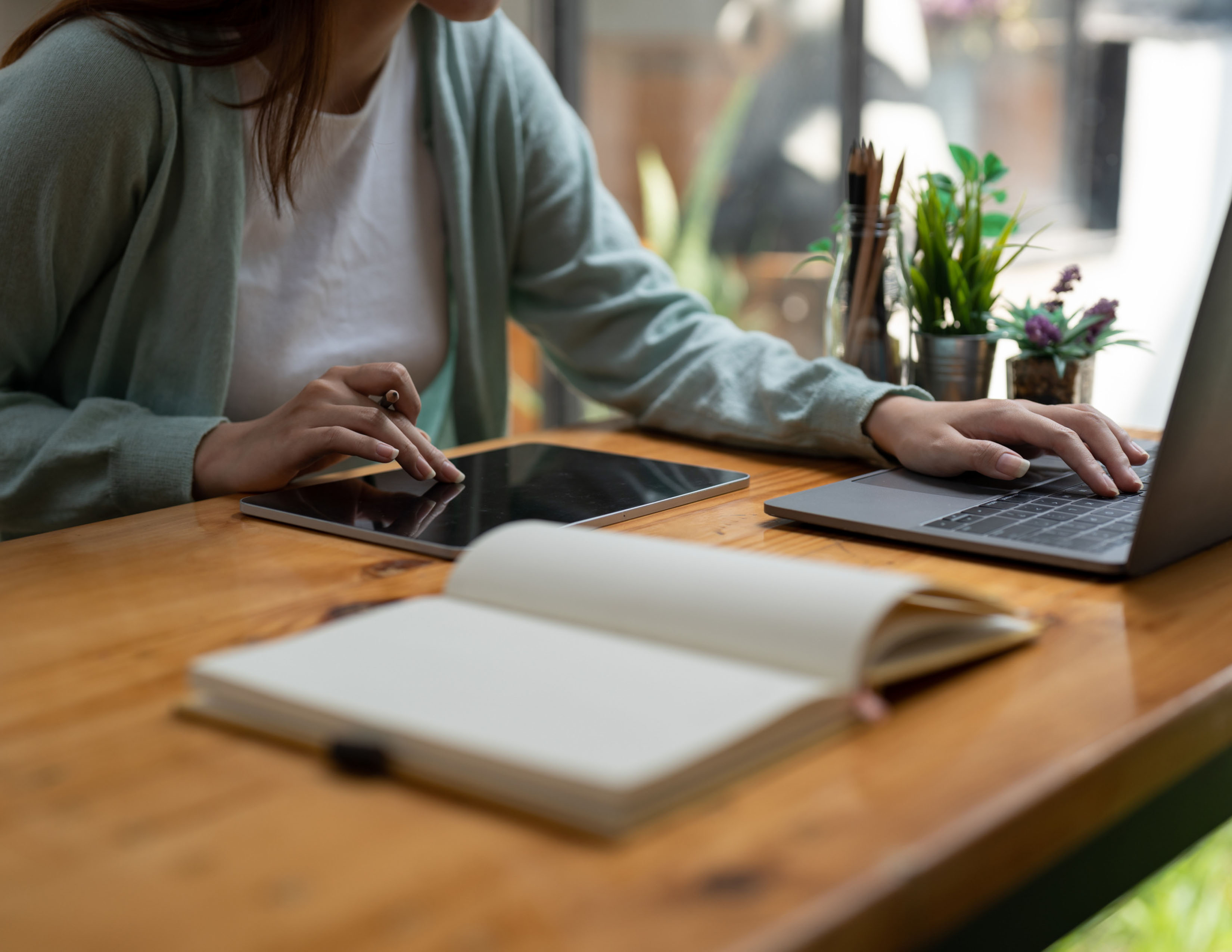 Student at desk with computer, open notebook and tablet.