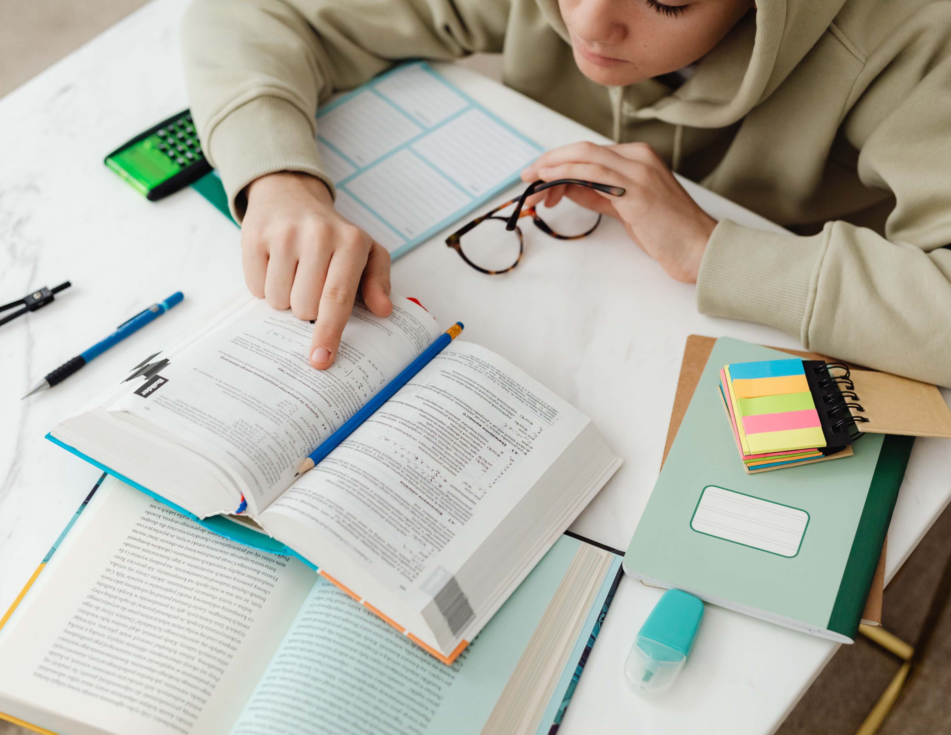 Picture of student reading a textbook on a cluttered table