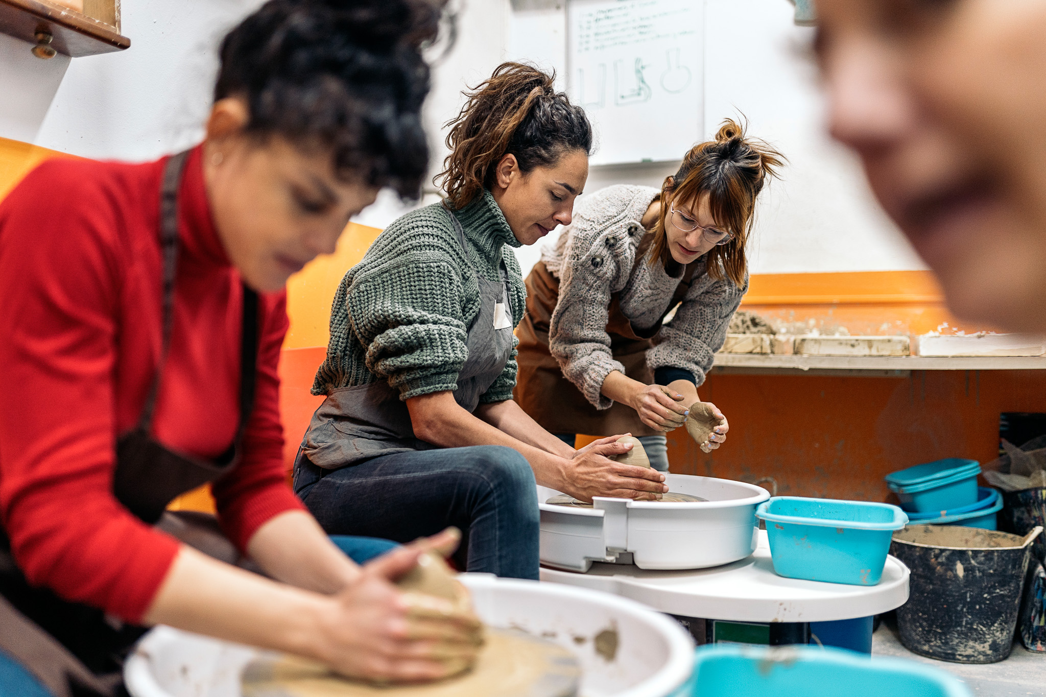 Group of students throwing clay on pottery wheels 