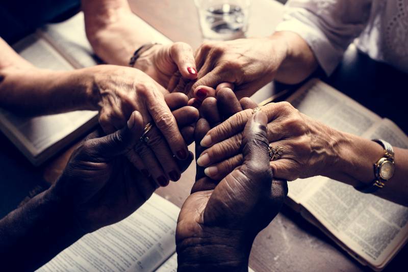 Hands inter-clasped with books open on the table
