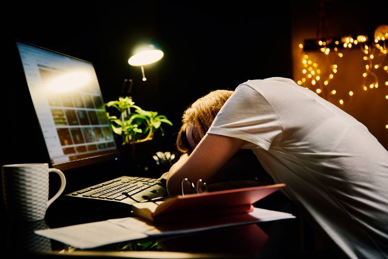 Tired woman works late at home workplace