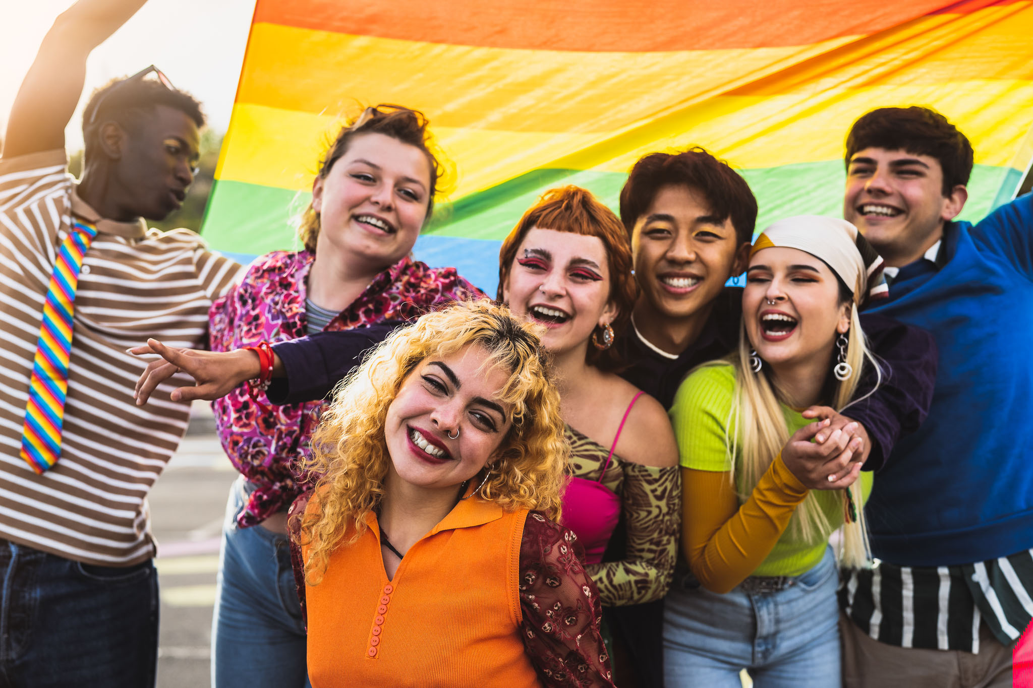 A diverse group of students with a rainbow flag.