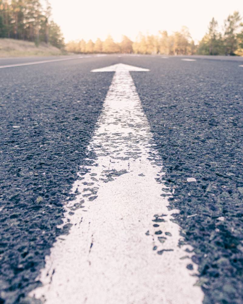 Conceptual image of an asphalt road and a direction arrow, the arrow on the road indicates