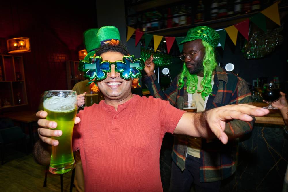 Happy man with a glass of beer and clover glasses dancing