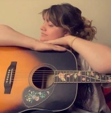 Photo of Heather Hall posing on an acoustic guitar 