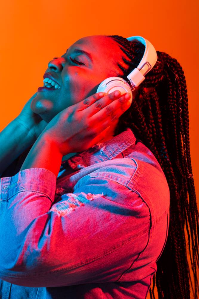 Black woman with her hair in braids listening to music via headphones